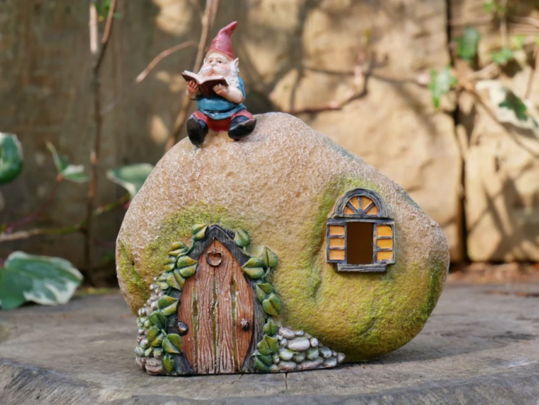 Reading gnome sitting on his rock house